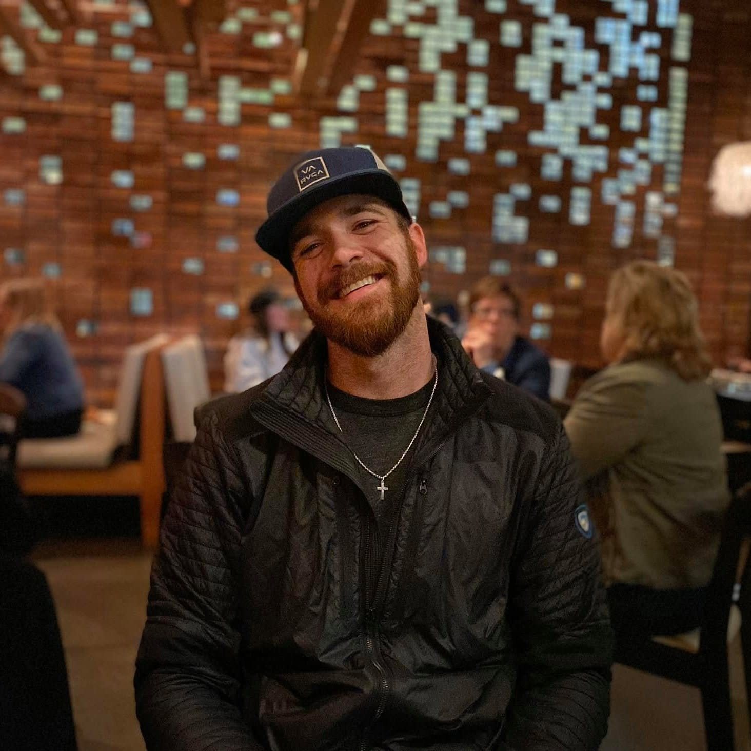 Corey Putney, founder of Corner Post Web, smiling in a navy cap and black jacket at a restaurant table